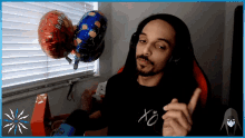a man wearing headphones and a shirt that says xo is sitting in front of balloons