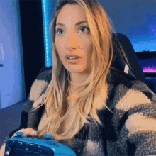 a woman is holding a blue video game controller and making a surprised face .