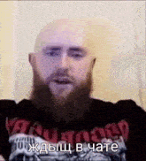 a bald man with a beard is wearing a black shirt and talking in russian .