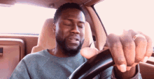 a man sitting in a car with his eyes closed holding the steering wheel