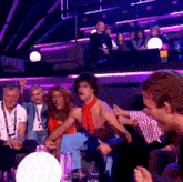 a group of people are sitting in a dark room with purple lights behind them