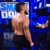 a shirtless wrestler stands in front of a sign that says smack down