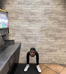 a man stretches his legs in front of a soda machine that says refresh