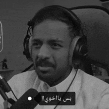 a man wearing headphones is talking into a microphone with a tag that says ' arabic ' on it