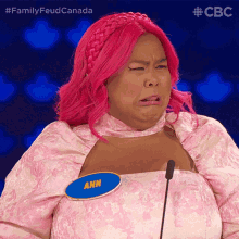 a woman with pink hair has a blue name tag that says ann