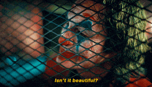 a close up of a clown behind a chain link fence with the words isn 't it beautiful below him
