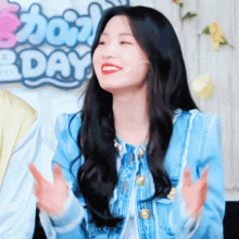 a woman in a blue jacket is smiling in front of a sign that says b day