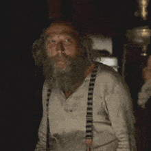 a man with a beard is wearing suspenders and a white shirt