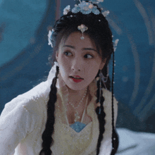 a woman in a white dress with pearls and flowers on her hair