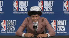 a man sitting in front of a sign that says nba draft 2025