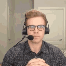 a man wearing glasses and headphones with a microphone on his mouth .
