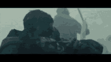 a man is carrying a dead man on a stretcher in a foggy scene .