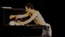 a man without a shirt is standing in front of a table with cups and a bottle on it .