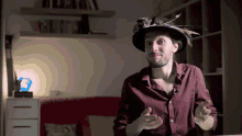 a man wearing a hat with feathers on it is talking