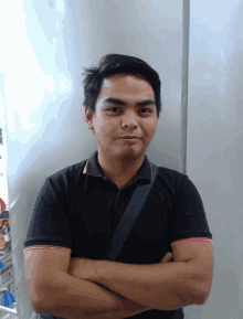 a man with his arms crossed wearing a black polo shirt