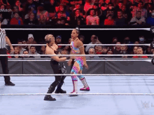 two women are wrestling in a wrestling ring with a referee watching