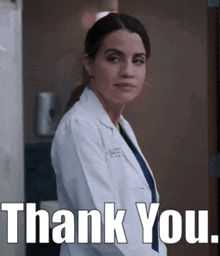 a woman in a lab coat is standing in front of a door and says thank you .