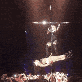 a woman is hanging from a pole while holding a microphone