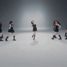 a woman in a black dress is surrounded by other women in black boots