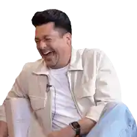 a man wearing a watch is laughing while sitting on a chair