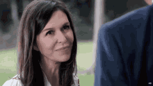 a woman in a white shirt smiles while looking at a man in a blue jacket