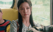a woman is sitting in a bus with a man and looking out the window .