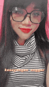 a woman wearing glasses and a striped shirt with the words kesayangan enggang written on the bottom