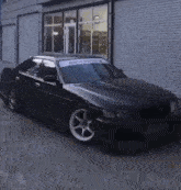 a black car is parked in front of a building with a white sticker on the windshield .