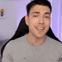 a man wearing a grey t-shirt and a white watch is smiling