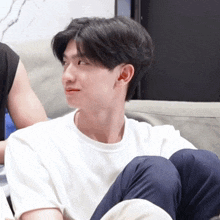a young man in a white shirt is sitting on a couch