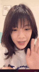 a young woman wearing a white champion shirt waves her hand