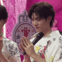 a man is holding a microphone in front of a pink sign that says tf