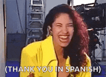 a woman in a yellow jacket is laughing and says `` thank you in spanish '' .