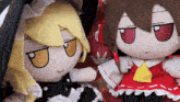 two stuffed dolls are sitting next to each other and one has a red ribbon around her neck