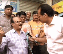 a man is talking into a microphone with a sign in the background that says real