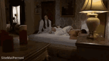 a woman in a white robe is laying on a bed next to a lamp and a candle