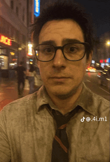 a man wearing glasses and a tie is standing in front of a building that says juice