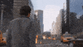 a man stands in the middle of a destroyed city looking at a taxi cab