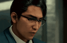a man wearing glasses and a suit is looking at something