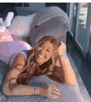 a woman is laying on a couch smiling and looking at the camera .