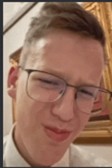 a close up of a young man wearing glasses and a white shirt .