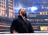 a man stands in a wrestling ring with a sign that says wre