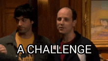 two men are standing next to each other in a room with the words `` a challenge '' written on their faces .