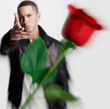 a man in a black jacket holds a red rose in his right hand