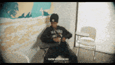 a man wearing a kenzo sweatshirt sits in a classroom