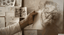 a person is holding up a piece of paper with a drawing of a person on it