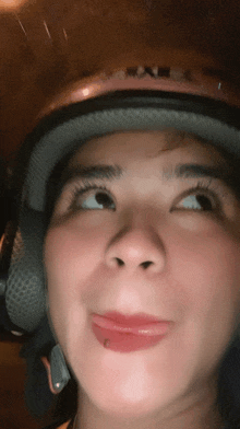 a close up of a woman wearing a helmet and making a face