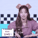 a girl wearing a bear headband sits at a table with a sign that says ' loves + ' on it