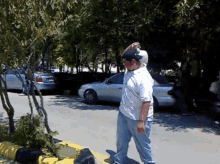 a man in a white shirt and blue jeans is standing on a street