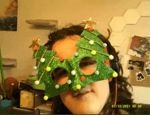 a woman wearing a christmas tree shaped mask takes a selfie